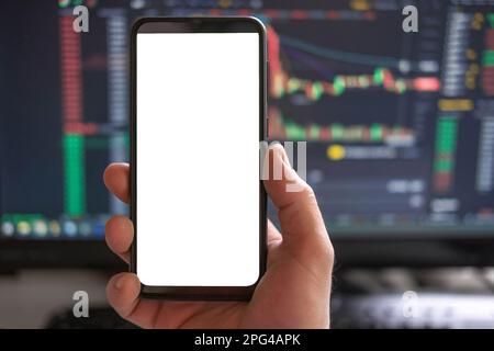 Schwarzes Telefon mit leerem Mockup-Bildschirm auf steigendem Aktiendiagramm. Nahaufnahme-Hand mit dem isolierten weißen Display des Smartphones. Online-Banking, Nutzung von Fonds-Apps. Fina Stockfoto