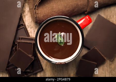 Tasse mit köstlicher heißer Schokolade mit frischen Minzblättern auf einem Holztisch, flach liegend Stockfoto