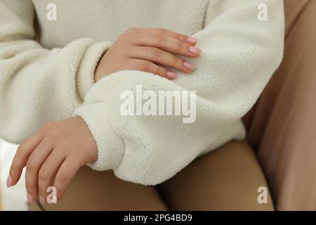 Eine Frau, die einen Pullover berührt, aus weichem, weißem Stoff, Nahaufnahme Stockfoto