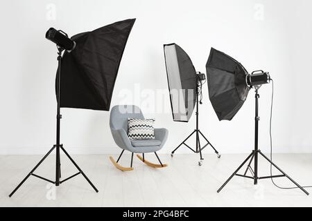 Komfortabler Schaukelstuhl und professionelle Beleuchtungsausstattung im Fotostudio Stockfoto