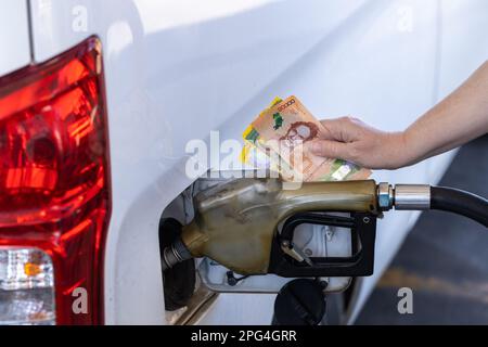 Costa Rica, Tankstelle, Frau mit einer Handvoll Geld am Auto, Konzept, steigende Benzinpreise, Betanken von Autos, Inflation in Costa Rica Stockfoto