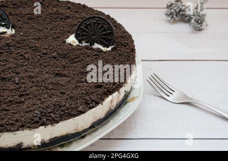 Käsekuchen mit Schokoladenkeks und einer Dessertgabel Stockfoto