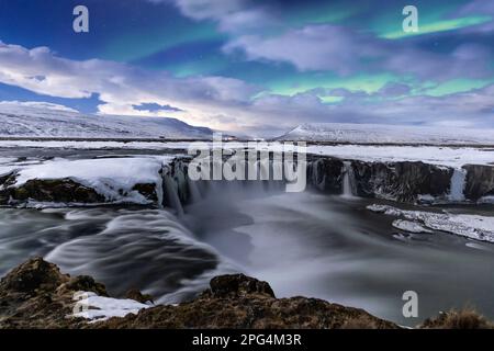 Aurora borealis über dem mondbeleuchteten Godafoss „Wasserfall der Götter“, Nordisland Stockfoto