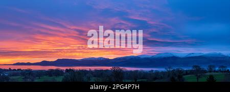 Sonnenaufgang über den schneebedeckten Snowdonia-Bergen über der Menai-Straße bei Beaumaris, Anglesey, Nordwales Stockfoto