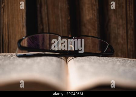 Offene verschwommene Seite mit hebräischem religiösen Text, Brille und alten, schäbigen jüdischen Büchern mit Lederbindung Chumash im Hintergrund. Lernbegriff Stockfoto