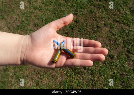 Zwei gelbblaue Gewehrkassetten mit AUFKLEBERSTAND MIT UKRAINE in der Hand (nationale Symbole der Ukraine). Konzept der militärischen Unterstützung für die Ukraine Stockfoto