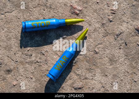 Zwei gelb-blaue Kartuschen mit der Aufschrift STOP WAR liegen auf einer Betonoberfläche (Nahaufnahme). Das Konzept der militärischen Unterstützung für die Ukraine Stockfoto