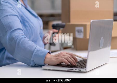 Frau überprüft Online-Bestellungen Laptop verwaltet Quittungen im Online-Shop. Barcode-Scanner wird verwendet Stockfoto