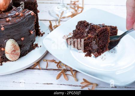 Männliche Hand hält ein Stück Schokoladenkuchen mit einer Gabel. Stockfoto