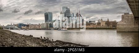 Blick auf HMS Belfast unter der Tower Bridge bei Ebbe auf der Themse. Auf der gegenüberliegenden Uferseite befindet sich die neue Entwicklung des Glasbaus Stockfoto