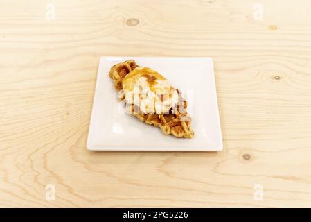 Ein frisch gebackenes Croissant mit Sahne und Dulce de leche Sirup auf einem unlackierten Holztisch Stockfoto