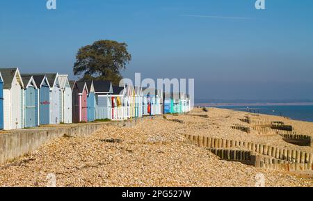 Eine Reihe geschlossener Strandhütten im Winter am Kiesstrand in Calshot Spit, Calshot UK Stockfoto