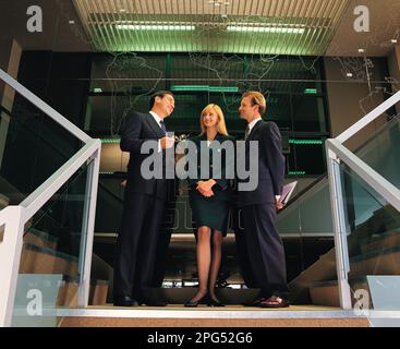 Drei Geschäftsführer stehen auf der Treppe in einem Geschäftsgebäude. Stockfoto