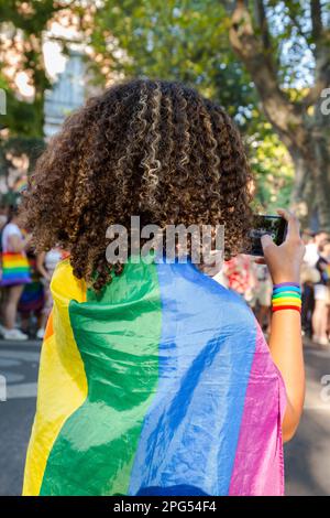 Afro-Frau mit stolzer Flagge. Afro-Mädchen macht ein Foto mit Handy. Für Gleichberechtigung kämpfen. Pride-Festival. LGBT-Stolz-Symbol. Stockfoto