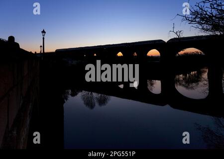 LNER Hitachi Azuma Zug überquert das Yarm Viadukt über dem Fluss Tees bei Sonnenuntergang und bildet eine Silhouette Stockfoto