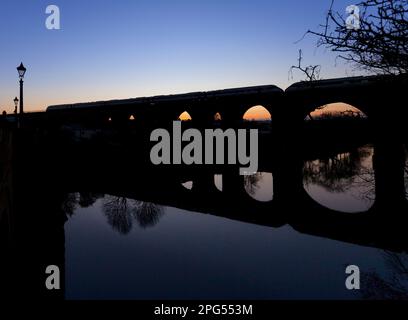 LNER Hitachi Azuma Zug überquert das Yarm Viadukt über dem Fluss Tees bei Sonnenuntergang und bildet eine Silhouette Stockfoto
