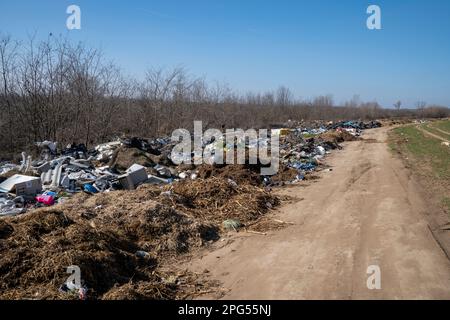 Erstaunliche Umweltverschmutzung in Ungarn. In der Nähe einer Stadt liegt eine Menge Müll neben einer unbefestigten Straße an der Grenze. Umweltverschmutzung. Illegales Dumping. Stockfoto