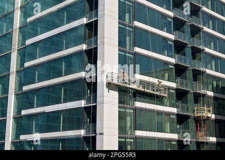 Austin, Texas, USA - Februar 2023: Fensterreiniger auf einer Wiege, die an der Außenseite eines Bürogebäudes im Stadtzentrum aufgehängt ist Stockfoto