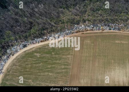 Erstaunliche Umweltverschmutzung in Ungarn. In der Nähe einer Stadt liegt eine Menge Müll neben einer unbefestigten Straße an der Grenze. Umweltverschmutzung. Illegales Dumping. Stockfoto