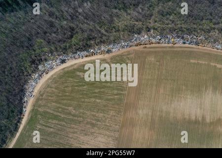 Erstaunliche Umweltverschmutzung in Ungarn. In der Nähe einer Stadt liegt eine Menge Müll neben einer unbefestigten Straße an der Grenze. Umweltverschmutzung. Illegales Dumping. Stockfoto