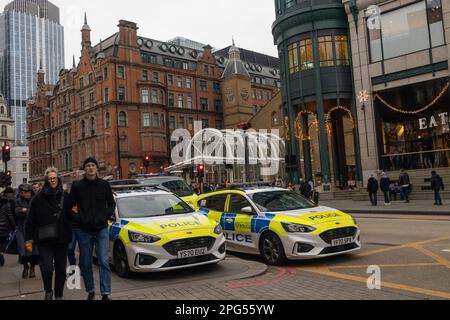 London, Großbritannien, -15. Dezember 2022, Menschen gehen die Liverpool Street entlang während der Hauptverkehrszeit. Zwei Polizeiautos sind unterwegs. Straßenleben. Stockfoto