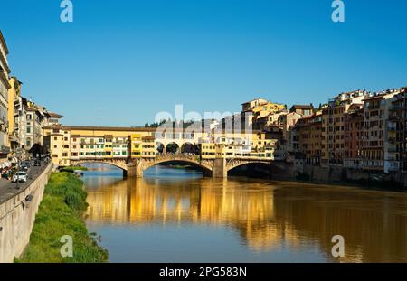 Die Ponte Vecchio in Florenz, Italien, wirft am späten Nachmittag Reflexionen im Arno an einem hellen Frühlingstag. Stockfoto