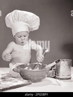 1960S BABY TRÄGT CHEF'S HAT ZUTATEN IN EINER SCHÜSSEL MISCHEN - B21859 HAR001 HARS ZUTATEN B&W HUMORABENTEUER KARRIERE KOMISCHE BERUFE KONZEPTKULINARISCHES COMEDY BABY BOY JUGENDLICHER KAUKASISCHE ETHNIZITÄT KOCH-SPEISENZUBEREITUNG HAR001 ALTMODISCH Stockfoto