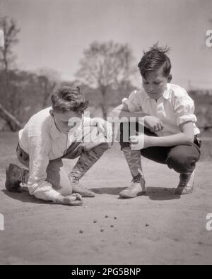 1920S 1930S ZWEI JUNGEN KNIEN IN MARMOR UND TRAGEN SLIP-HOSEN, HOHE GEMUSTERTE SOCKEN UND HI TOP SPEEDSTER-SCHUHE - B6983 HAR001 HARS ERSCHIESSEN MÄNNLICHE GESCHWISTER B&W KNIEND MURMELN HOCHWINKEL ABENTEUER FREIZEIT UND AUFREGENDE ERHOLUNG GESCHWISTER HI FRIENDLY KNUCKLE DAUNEN STILVOLLE KURZE HOSEN GEMUSTERT WACHSEN JUGENDLICHE JUGENDLICHE JUGENDLICHE JUGENDLICHE JUGENDLICHE JUGENDLICHE JUGENDLICHE JUGENDLICHE JUGENDLICHE ZUSAMMENGEHÖRIGKEIT SCHWARZ-WEISS WEISSE ETHNISCHE ZUGEHÖRIGKEIT HAR001 KNIEND ALTMODISCH Stockfoto