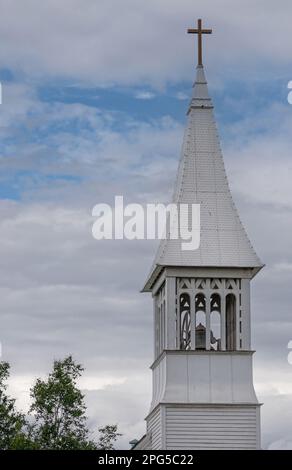 Fairbanks, Alaska, USA - 27. Juli 2011: Nahaufnahme der historischen katholischen Kirche mit weißem Holz und unbefleckter Empfängnis vor blauer Wolkenlandschaft. Grünes Laub Stockfoto