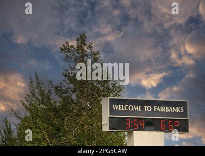 Fairbanks, Alaska, USA - 27. Juli 2011: Begrüßungsschild außerhalb des Flughafens mit Uhrzeit und Temperatur unter blauer Wolkenlandschaft und grünem Laub dahinter Stockfoto