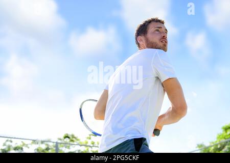 Tennisspieler, der das Spiel spielt, der Ball fertigstellt, servieren Sie draußen. Sportsportler draußen mit Tennisschläger. Passender junger männlicher Kaukasier Stockfoto