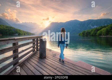 Frau und Berge spiegeln sich im See bei Sonnenuntergang im Herbst Stockfoto