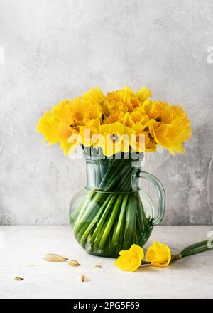 Stillleben mit gelben Narzissen in einer alten Glaskanne. Hausgemachte Dekoration für Ostern oder Muttertag. Speicherplatz kopieren. Stockfoto