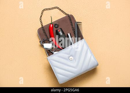 Beutel mit Spray, Chili-Pfeffer und Zubehör auf beigefarbenem Hintergrund Stockfoto