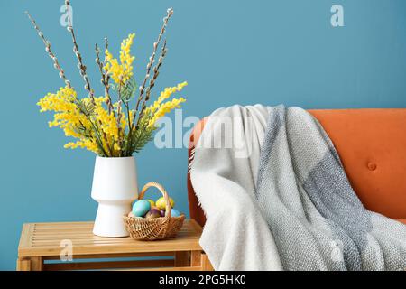 Blumenvase und Korb mit bemalten Eiern auf dem Tisch im Wohnzimmer Stockfoto