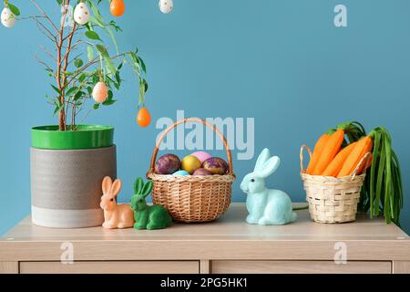 Osterdekorationen auf einem Holzschrank in der Nähe der blauen Wand Stockfoto