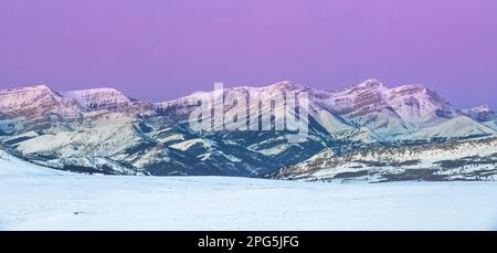 Panoramablick über den Himmel vor der Dämmerung über dem Dampfbootberg entlang der felsigen Bergfront im Winter bei augusta, montana Stockfoto