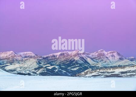 Im Winter bei augusta, montana, erstrahlt der Himmel vor Sonnenaufgang über dem Dampferberg an der felsigen Bergfront Stockfoto