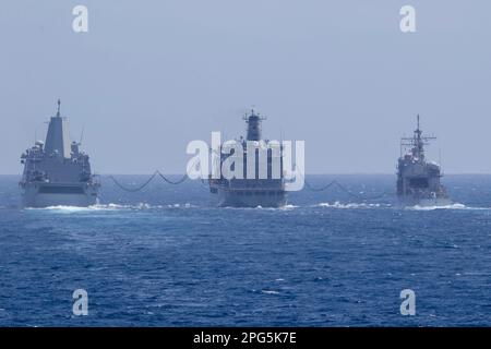 OSTCHINESISCHE SEE (17. März 2023) – Henry J. Kaiser Class läuft Nachfüllöl USNS John Ericsson (T-AO 194), Center, entsendet Kraftstoffsonden zur Amphibienrampe USS John P. Murtha (LPD 26), Left, und Ticonderoga Class Cruiser USS Shiloh (CG 67) beim Tanken auf See, 17. März 2023. Befehlshaber der Logistikgruppe Westpazifik (COMLOG WESTPAC)/Task Force 73 liefert logistisch stationierte Einheiten im Indo-Pazifik zusammen mit regionalen Alliierten und Partnern nach. Makin Island Amphibious Ready Group, bestehend aus dem Amphibienschiff USS Makin Island (LHD 8) und Amphibienfahrzeug Trans Stockfoto