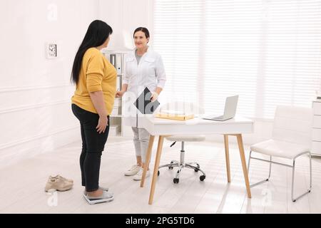 Übergewichtige Frau auf Waage während der Beratung mit dem Ernährungsberater in der Klinik Stockfoto