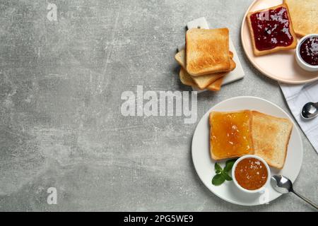 Köstliche Toasts mit Marmelade, serviert auf einem hellgrauen Tisch, flach liegend. Platz für Text Stockfoto