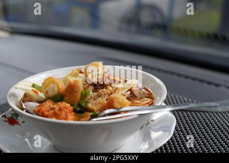 Soto Mie Bogor oder Nudelsuppe mit Frühlingsrollen aus Bogor ist authentische indonesische traditionelle Küche. Im Auto erschossen. Stockfoto