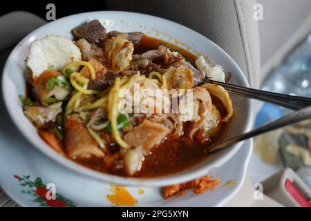 Soto Mie Bogor oder Nudelsuppe mit Frühlingsrollen aus Bogor ist authentische indonesische traditionelle Küche. Im Auto erschossen. Stockfoto