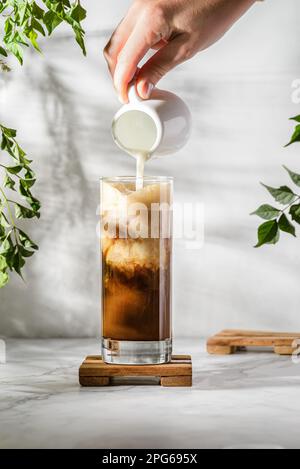 eiskaffee und Milch auf einem weißen Tisch, Frappe mit Eis, Mehl auf dem Tisch. Hochwertiges Foto Stockfoto
