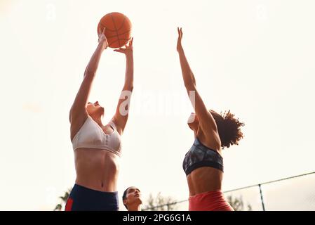 Willkommen in der Welt des Wettkampfsports. Eine vielfältige Gruppe von Sportlerinnen, die tagsüber gemeinsam ein Wettkampfspiel mit Basketball spielen. Stockfoto