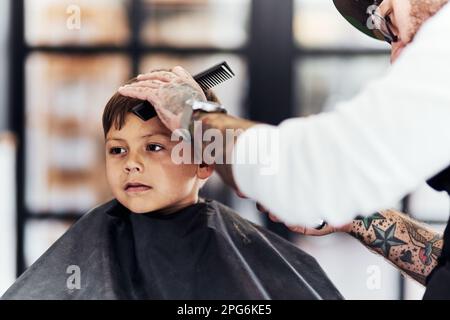 Alle werden über meine coole Frisur in der Schule plaudern. Cropped hat einen süßen kleinen Jungen erschossen, der sich beim Friseur die Haare schneiden ließ. Stockfoto