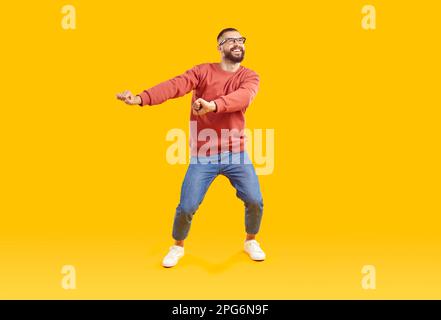 Fröhlicher und positiver Mann mit guter Laune, der Spaß beim Tanzen auf gelbem Hintergrund hat. Stockfoto