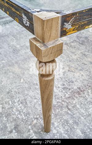 Holzschnittiger Schenkel aus massiver Eiche mit Metalltischrahmen während des Herstellungsprozesses des Esstisches in der Werkstattnahansicht Stockfoto