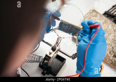 Servicetechniker testet neuen RAM-Speicherchip mit Digitalmultimeter am Laptop. Notebook-Konzept reparieren und aufrüsten. Schließen. Stockfoto