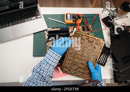 Weibliche Hände reparieren Computerdetails und verwenden Laptop auf dem Tisch, Draufsicht. Stockfoto